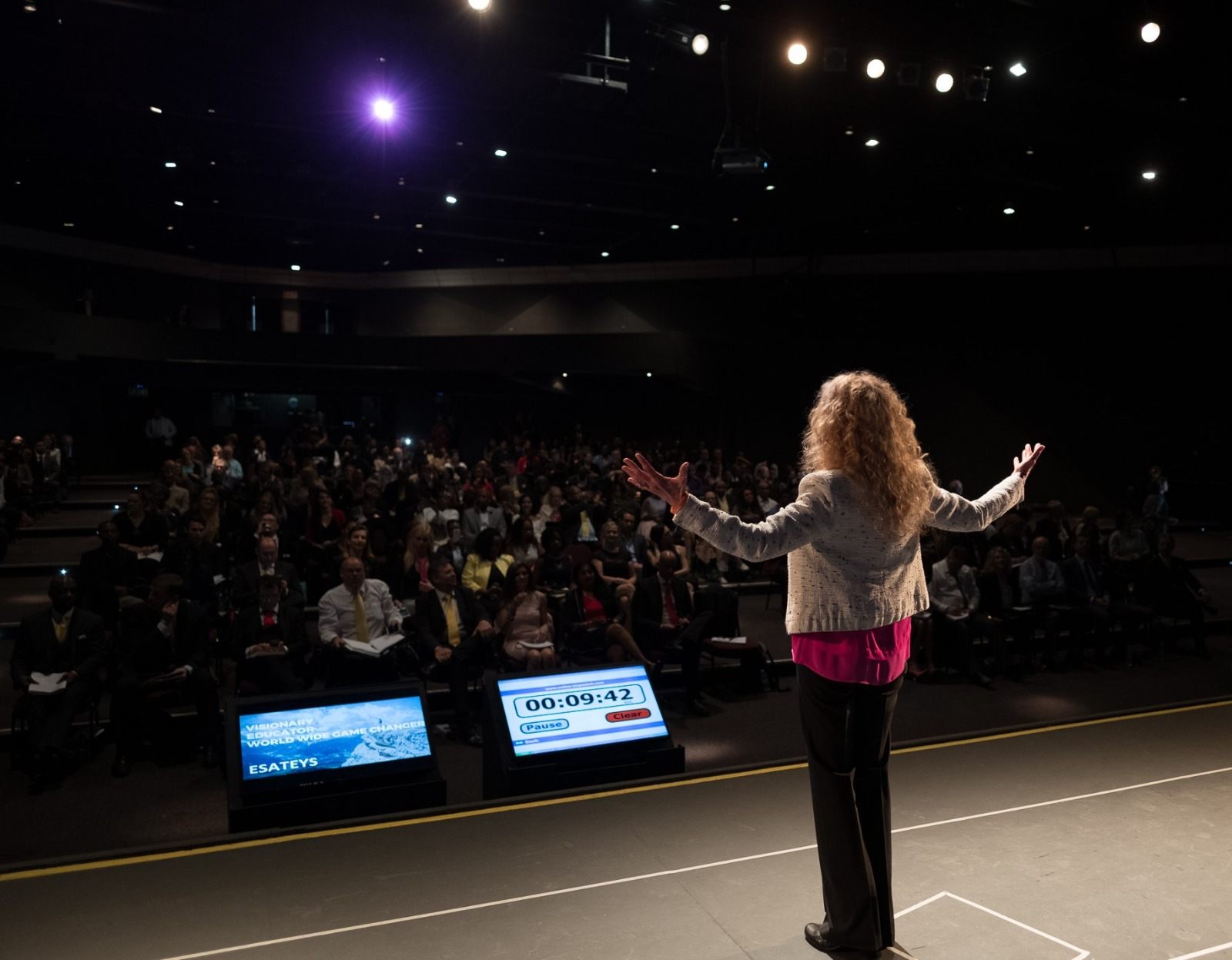Esateys on stage, speaking to a full auditorium